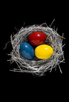 nest with three color Easter eggs on black bacground