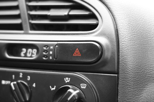 Car emergency lights button on cockpit. Very shallow DOF, focus on triangles on emergency lights button.