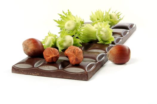 Piece of chocolate and wood nuts on a white background