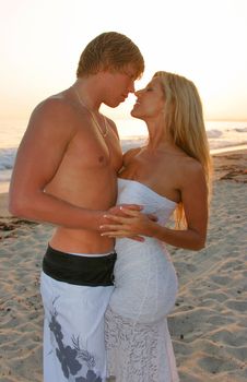 Young Couple embraces on the Beach at Sunset
