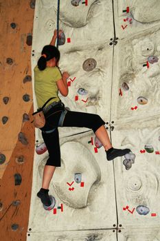 female rock climber inside an indoor rock climbing wall
