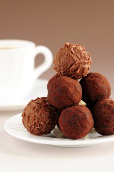 Gourmet chocolate truffles on a plate with a cup of coffee