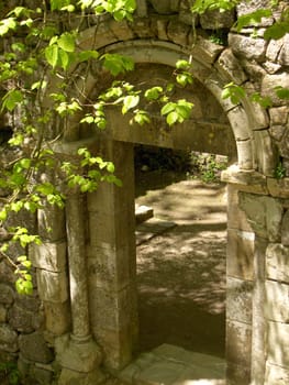 Vines and bushes creep in on an old arched doorway in a ruined castle near Sintra, Portugal.