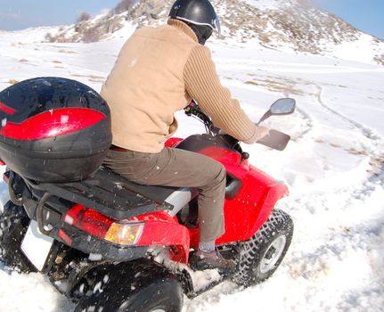 Man riding quad in mountain snow