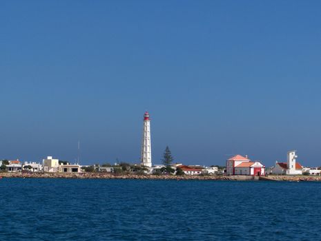 A lighthouse and white buildings in a village in the Algarve region of Portugal.