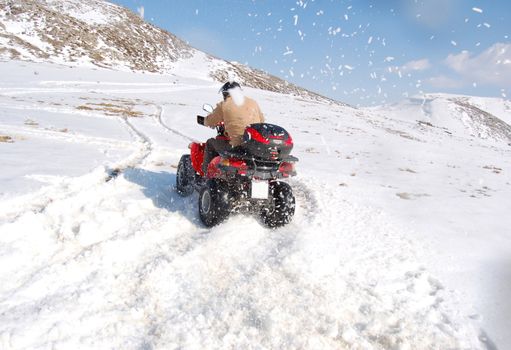 Man riding quad in mountain snow