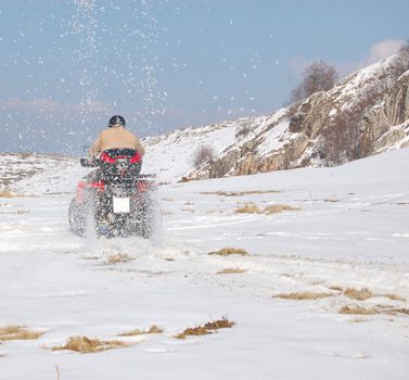 Man riding quad in mountain snow