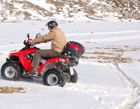 Man riding quad in mountain snow