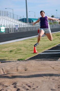 Teenage girl practicing long jump              