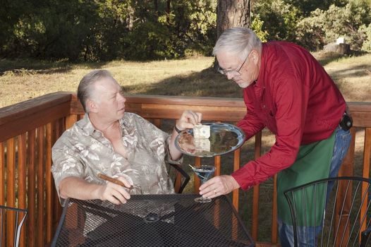 Waiter delivering a cocktail to a customer at an outdoor restaurant/bar