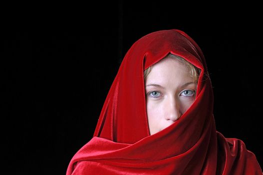 Beautiful young blond woman that has a piercing look, with red shawl across face and head