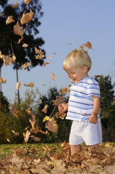 Young infant playing in falling leaves