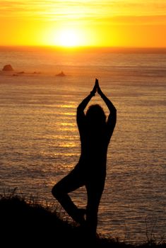 Woman doing yoga exercises at sunset on the West coast