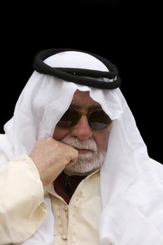 older middle-eastern man with white beard, in Arabian headress and sunglasses isolated on black