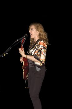 singer/Guitarist playing while isolated on black during live concert