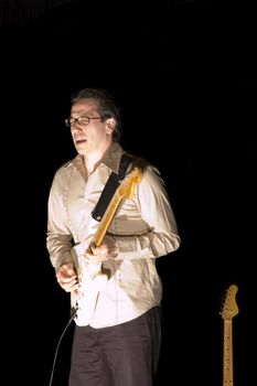 lead Guitarist playing while isolated on black during live concert