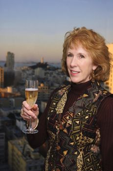 middle aged Woman celebrating with champagne in san Francisco with Coit tower in the background