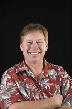 Happy smiling casual businessman in a floral Hawaiin style shirt over a black background