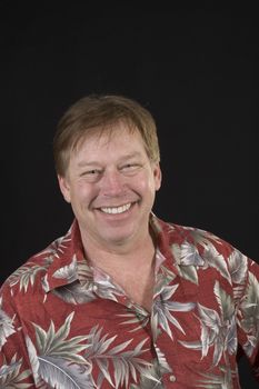Happy smiling Middle-aged man (50ish)  in Hawaiian floral shirt isolated on black