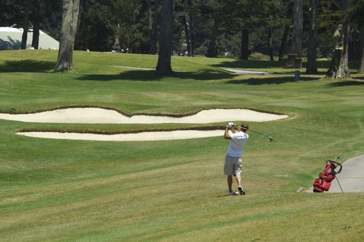 Golfer at end of swing with traps in front of him