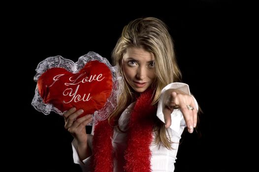 Attractive young woman with a valentines message on a pillow, over a black background