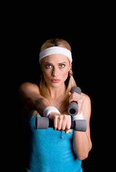 Young blond sportswoman exercising with weights  over a black background