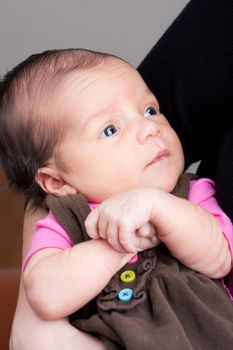 A newborn baby being held in the arms of her mother.