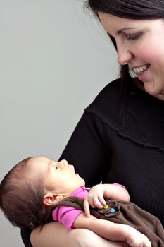 A newborn baby being held in the arms of her mother.