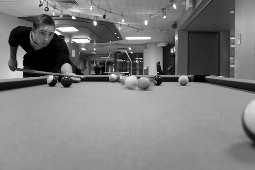 A young man shooting pool with motion blur on the pool balls. Shallow depth of field.