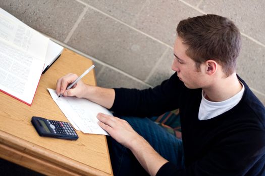 A young high school or college student working on his math homework.