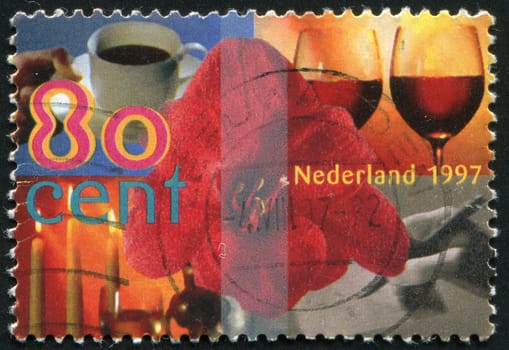 NETHERLANDS - CIRCA 1997: Amaryllis surrounded by cup of coffee, two glasses of wine, hand writing card, candlelight, circa 1997.