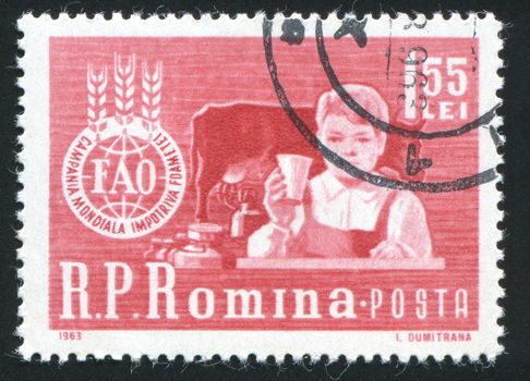 ROMANIA - CIRCA 1963: The charming kid. The boy sits at a table and �FAO� Emblem, circa 1963.