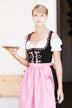 Bavarian Dirndl woman serving coffee on the pasture