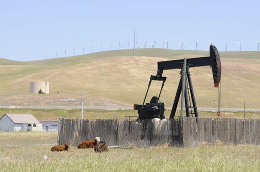 Oil well pump with wind generators in the background, showing old and new technology, or renewable and non renewable resources in northern California