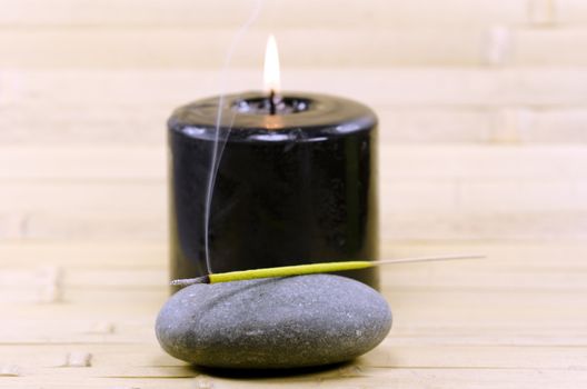 a black candle and a stone with a incense stick in the foreground