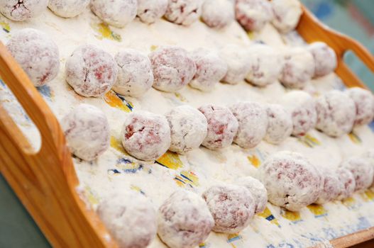 Meat ball in the flour on a tray ready to be cooked