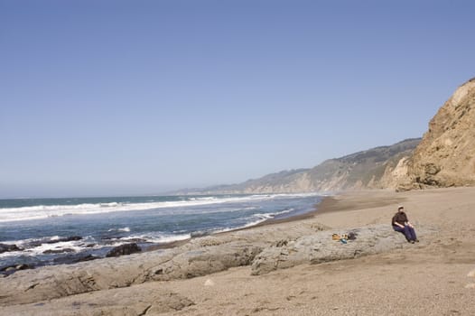 Woman hiker on remote rugged beach in Northern California 