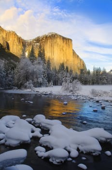 View of beautiful Yosemite valley in winter with the Merced river and snow covered El Capitan at sunset