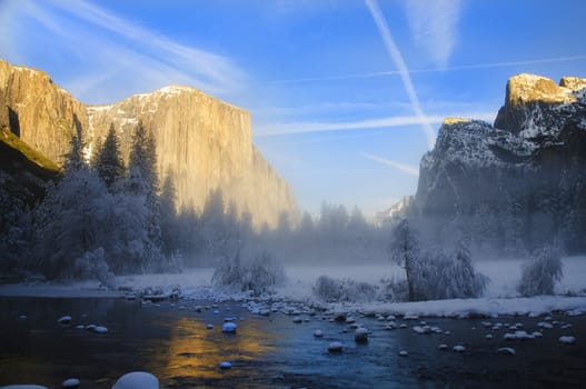 View of beautiful Yosemite valley in winter with the Merced river and snow covered El Capitan at ssunset