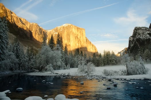 Yosemite valley at sunset with golden rays of sunlight on El Capitan and beautiful reflection from the Merced river in winter