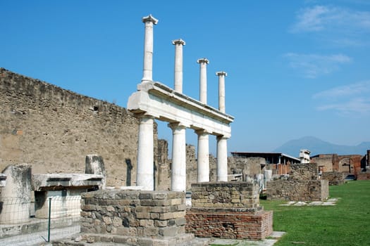 Columns that once supported a temple in Pompeii with mount Vesuvius in the distance