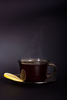 Cup of tea with lemon on a black background