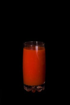 Glass of tomato juice on a black background