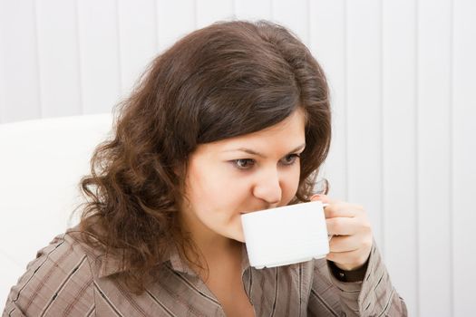portrait of a young brunette woman drinking coffee from a cup
