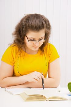 a young woman student wearing glasses reading a book

