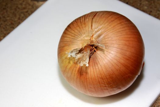 A close-up of a large yellow onion sitting on a cutting board.
