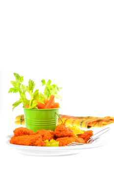 Plate of hot and spicy buffalo wings with fresh vegetables.