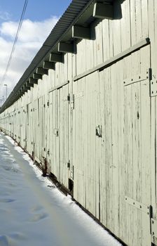 Long row of green storage sheds on a snowy winter day