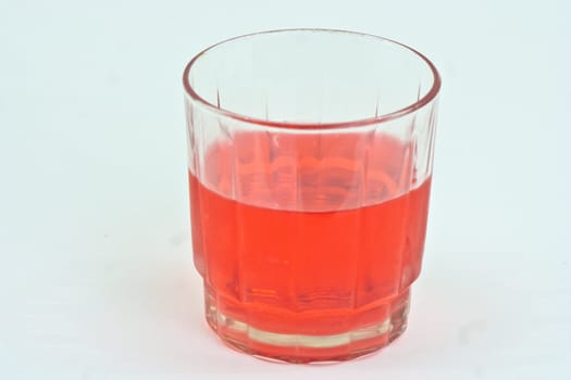 Glas half full with red drink on a white background.