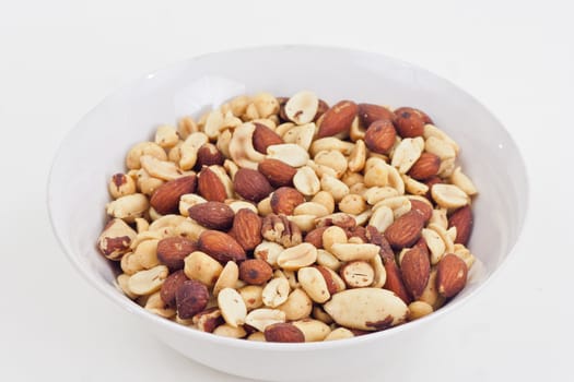 Mixed nuts ain a white bowl on a white background.